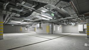 Empty, new, underground parking garage interior. At the ceiling is located electrical system and air condition.