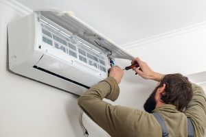 Technician installing new air conditioner. Modern air conditioner during the installation process. Worker installs indoor unit of the air conditioner.